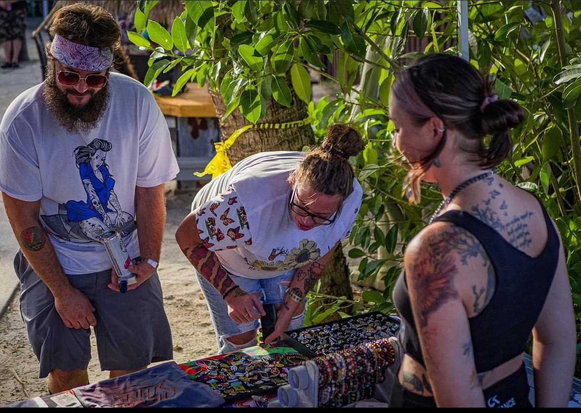 Shoppers browsing handmade bracelets, rings and enamel pins at the Mad Mellow pop-up table outdoors